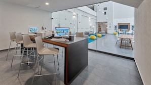 A modern office space with a central desk area, multiple computer monitors, and a pool area visible through glass walls.