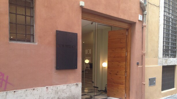 A hotel entrance with a glass door, a signboard, and a tiled entrance. - Adrianus Hotel (Rome)