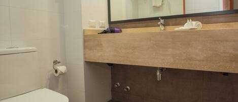 Une salle de bain comprenant des toilettes, un lavabo avec un miroir et un porte-serviettes.