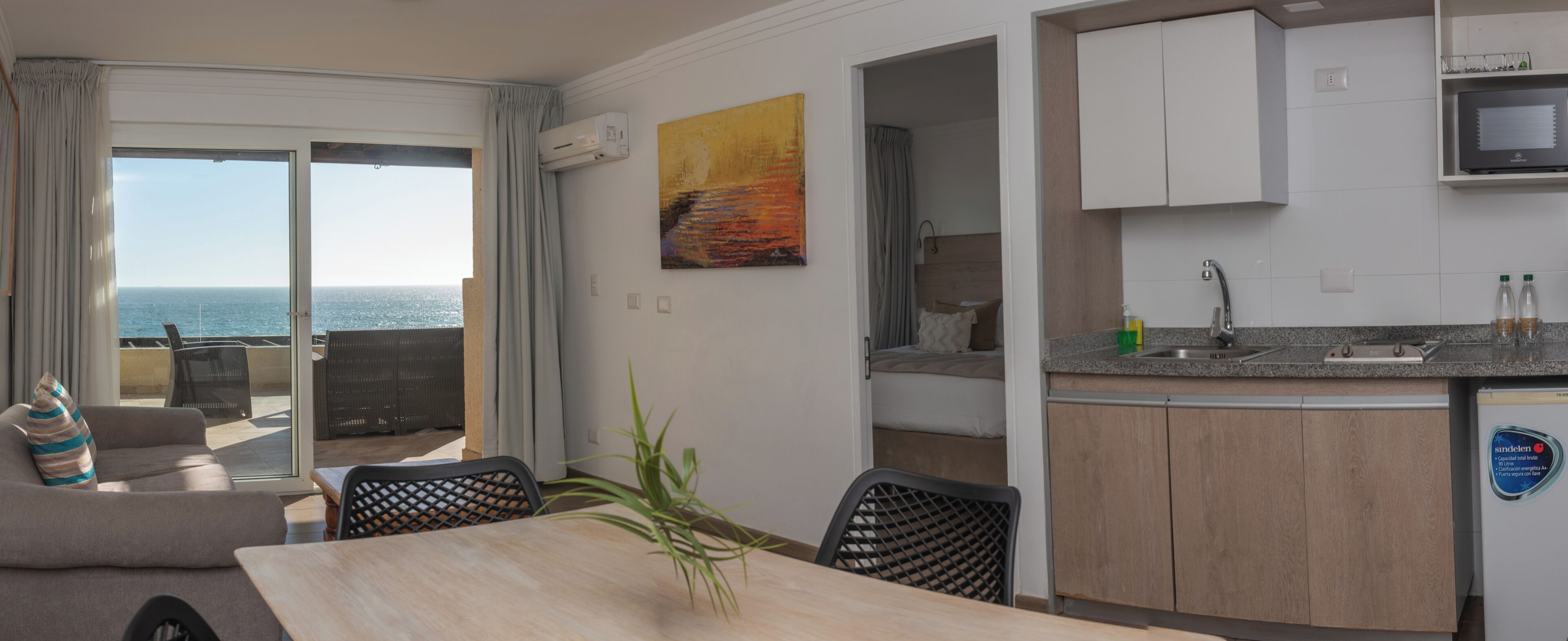A modern kitchen with a built-in microwave, a sink, and a dining area with a table and chairs.