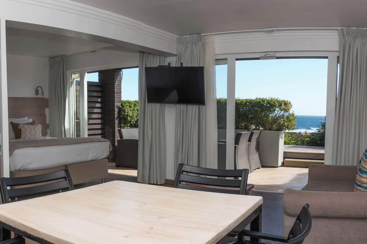 Habitación de hotel compacta con kitchenette, una cama, televisor y balcón con vistas.