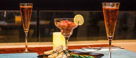 Una mesa dispuesta con dos copas de champán, un bol de mariscos y una vela.