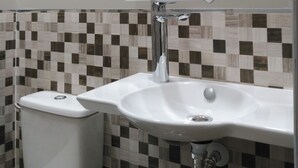 Une salle de bain avec un lavabo blanc, des toilettes et un miroir agrémenté de motifs décoratifs.