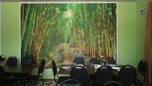 A conference room with a large bamboo forest mural on the wall, a wooden table, and black chairs. - Hotel Canyon (Khoni)
