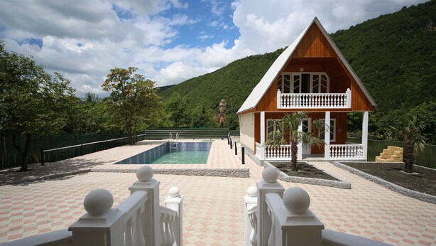 A wooden house with a balcony, a swimming pool, and a paved walkway. - Hotel Canyon (Khoni)