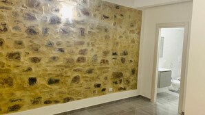 Un pasillo con pared texturizada y una puerta que da a un baño.