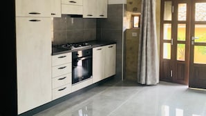 Una cocina moderna con armarios blancos, una estufa de acero inoxidable y un amplio ventanal con cortinas.