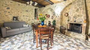 Un comedor rústico con pared de piedra, mesa de madera y baldosas de piso estampadas.