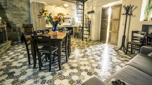 Un comedor con una mesa y sillas de madera, un florero con flores y una cocina al fondo.