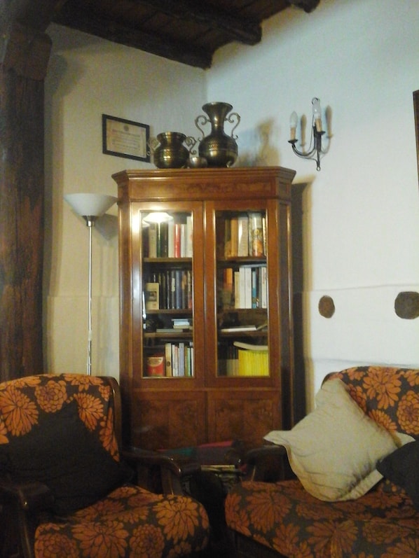 A cozy living room with a wooden bookcase, two patterned armchairs, and a white sofa. - Hotel Rural Restaurante La Posada de los Vientos (La Acebeda)