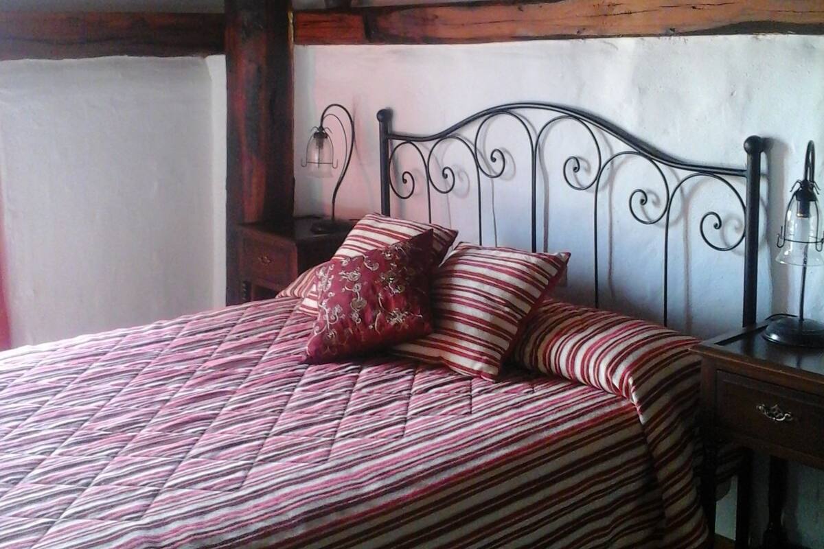 Ein Bett mit gestreifter Bettdecke, einem Zierkissen und einem Nachttisch mit Lampe.