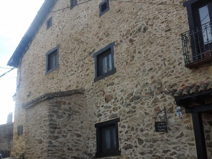 A stone building with multiple windows and a small balcony.