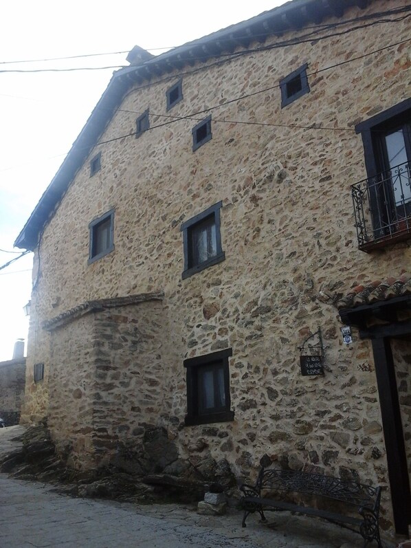 A stone building with multiple windows and a small balcony. - Hotel Rural Restaurante La Posada de los Vientos (La Acebeda)