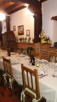 Una larga mesa de comedor dispuesta para una comida en una habitación rústica con paredes de ladrillo visto y vigas de madera.