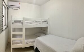 Cozy single-room accommodation with a bunk bed and separate bed, featuring a window and air conditioning unit.