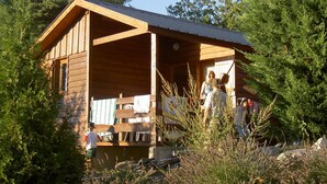 Une cabane en bois dotée d’un porche, entourée d’une végétation luxuriante.