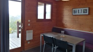 Une pièce de cabane en bois avec une table et des chaises, une fenêtre et un luminaire au plafond.
