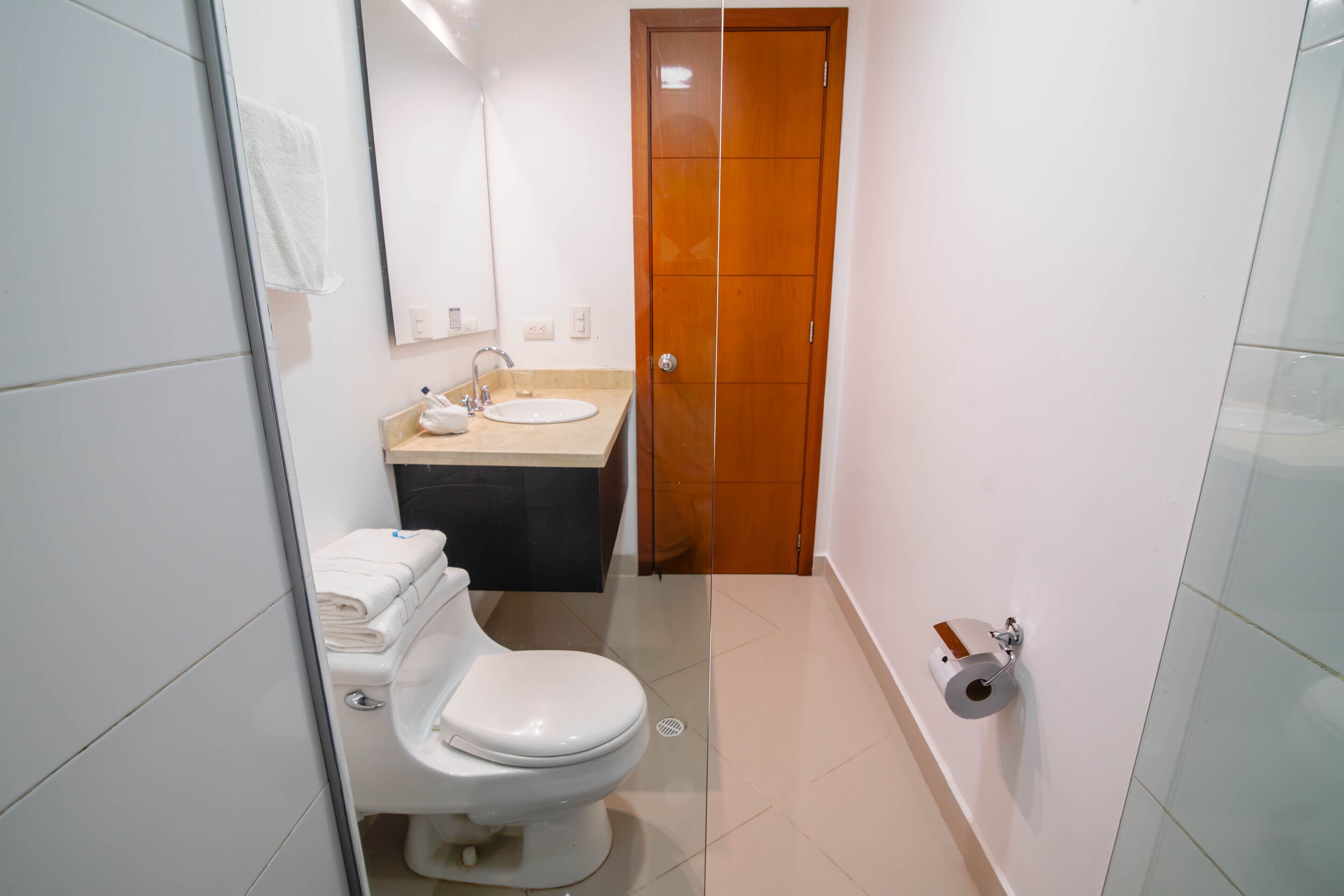 Een badkamer met toilet, wastafel en spiegel.