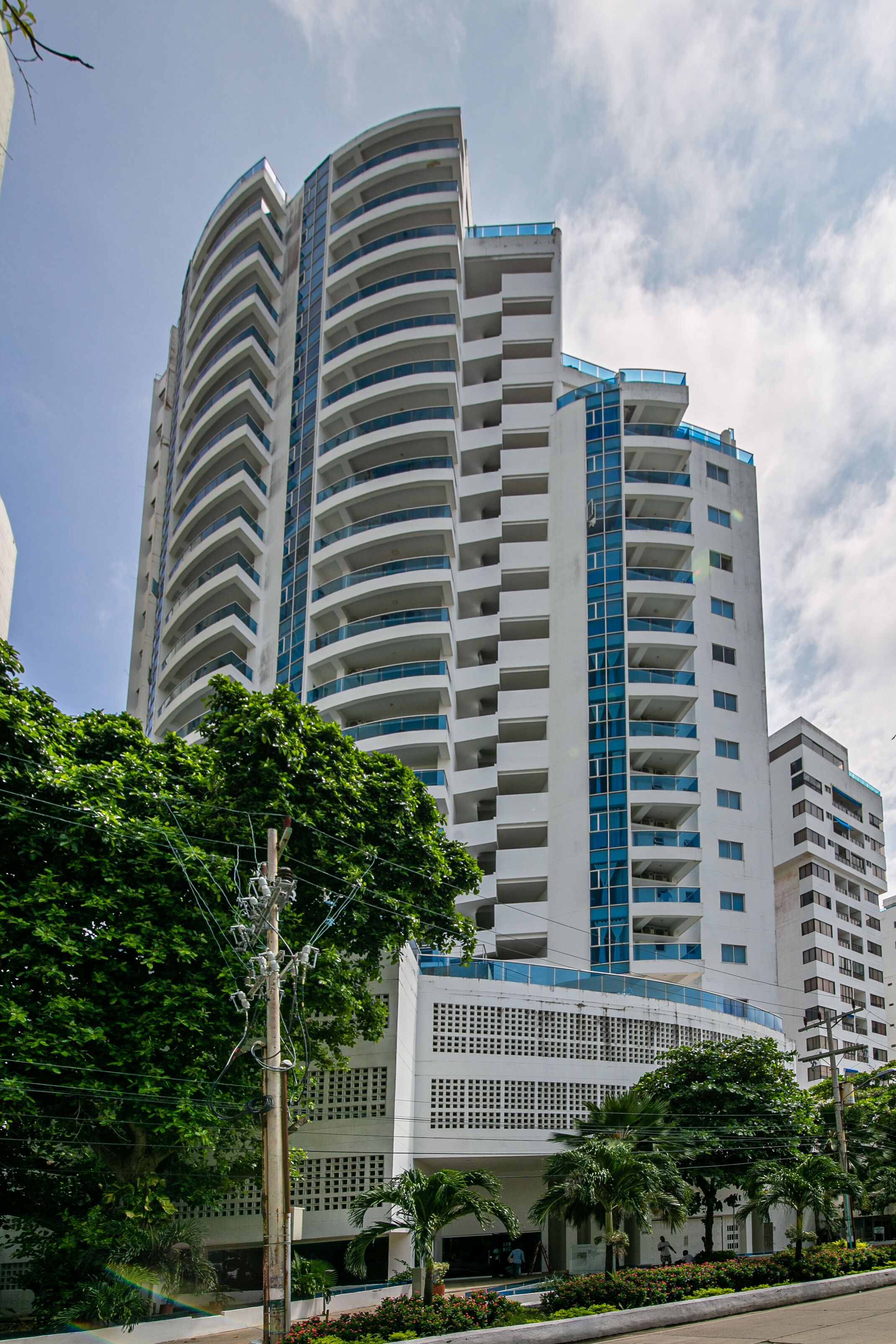 Un immeuble à plusieurs étages doté d’une façade incurvée, de balcons et d’une palette de couleurs blanche et bleue.