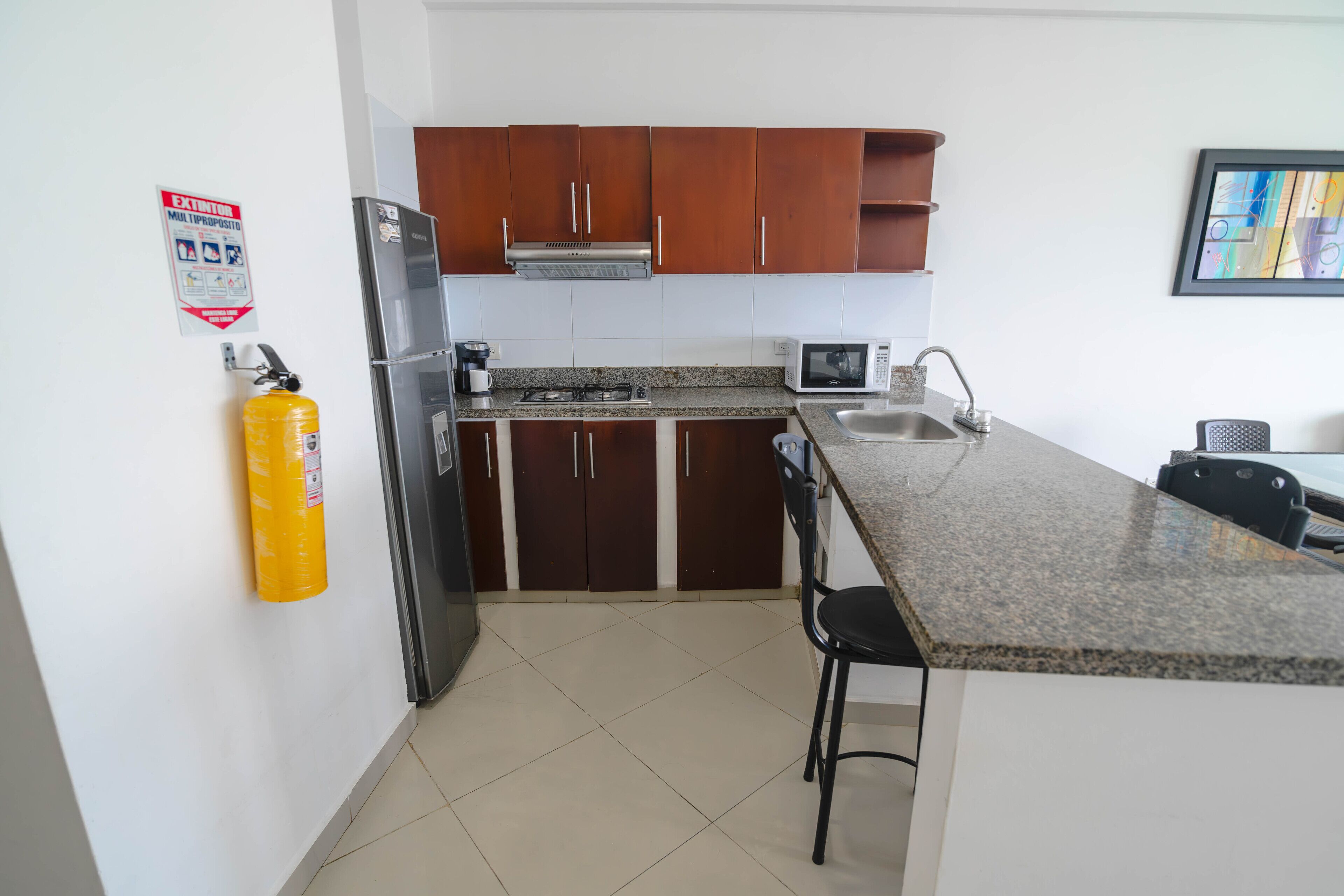 A compact kitchen with a refrigerator, stove, microwave, and sink.