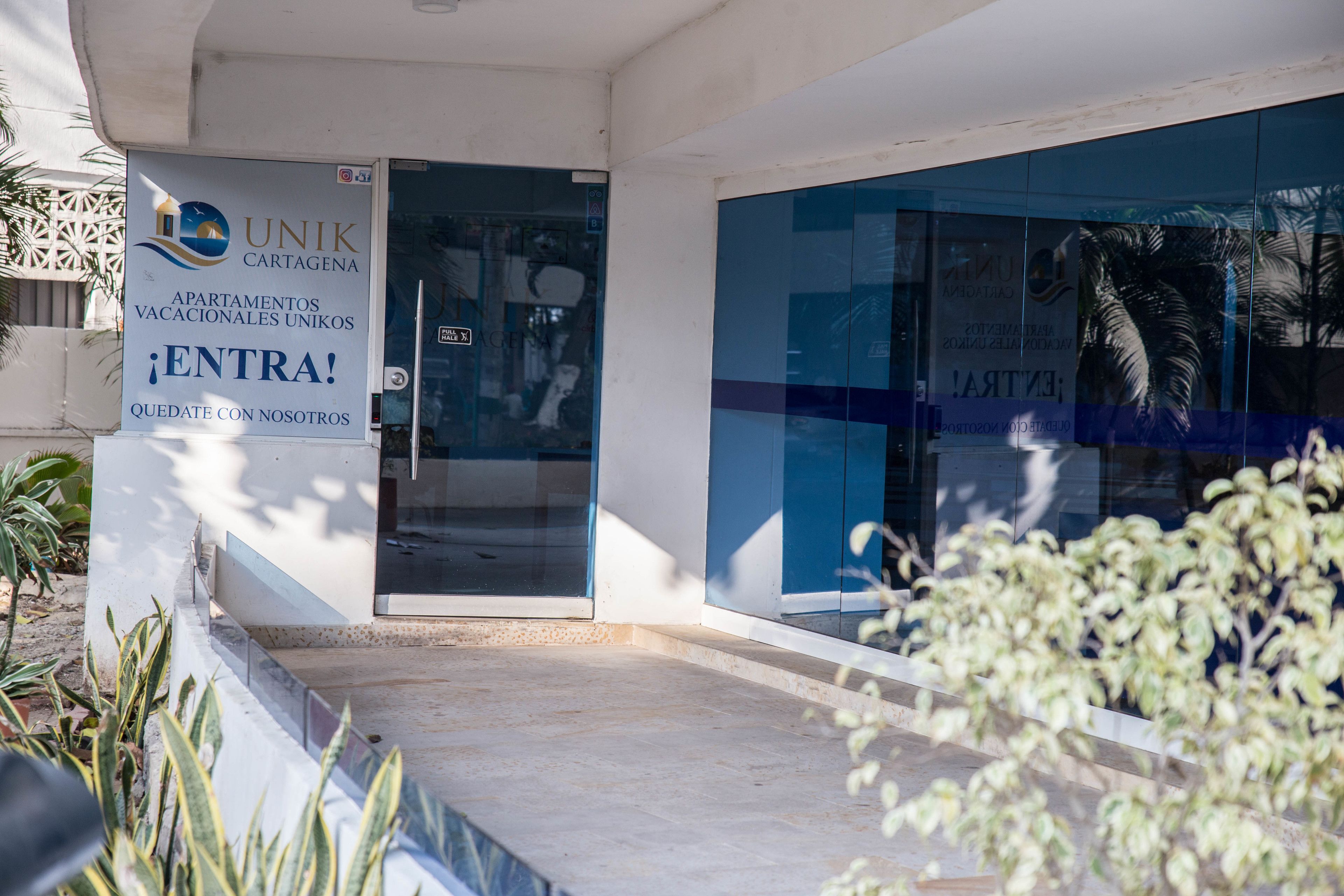 A building entrance with a sign for UNIK Cartagena apartments.