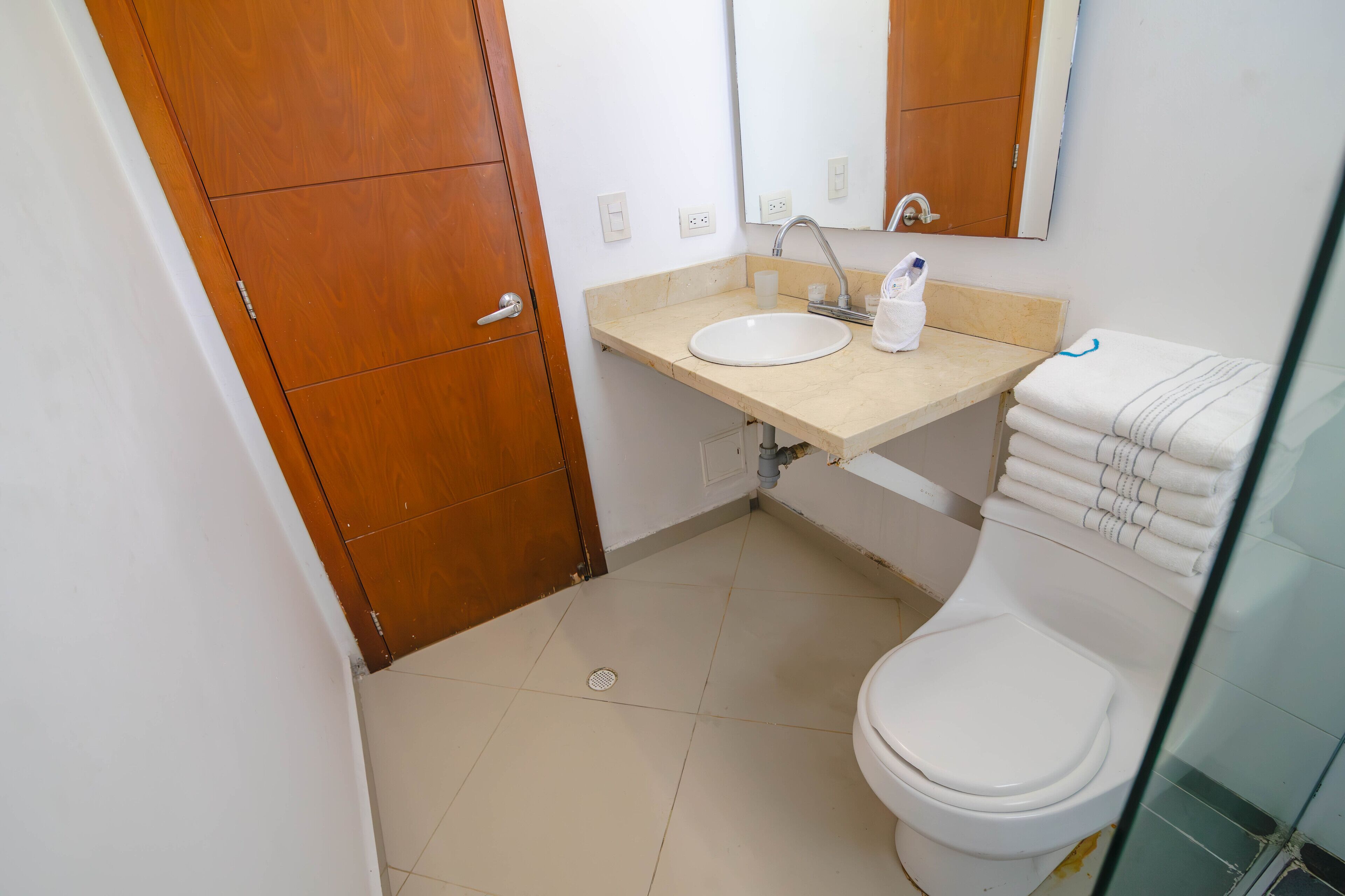 A small bathroom with a toilet, sink, and mirror.