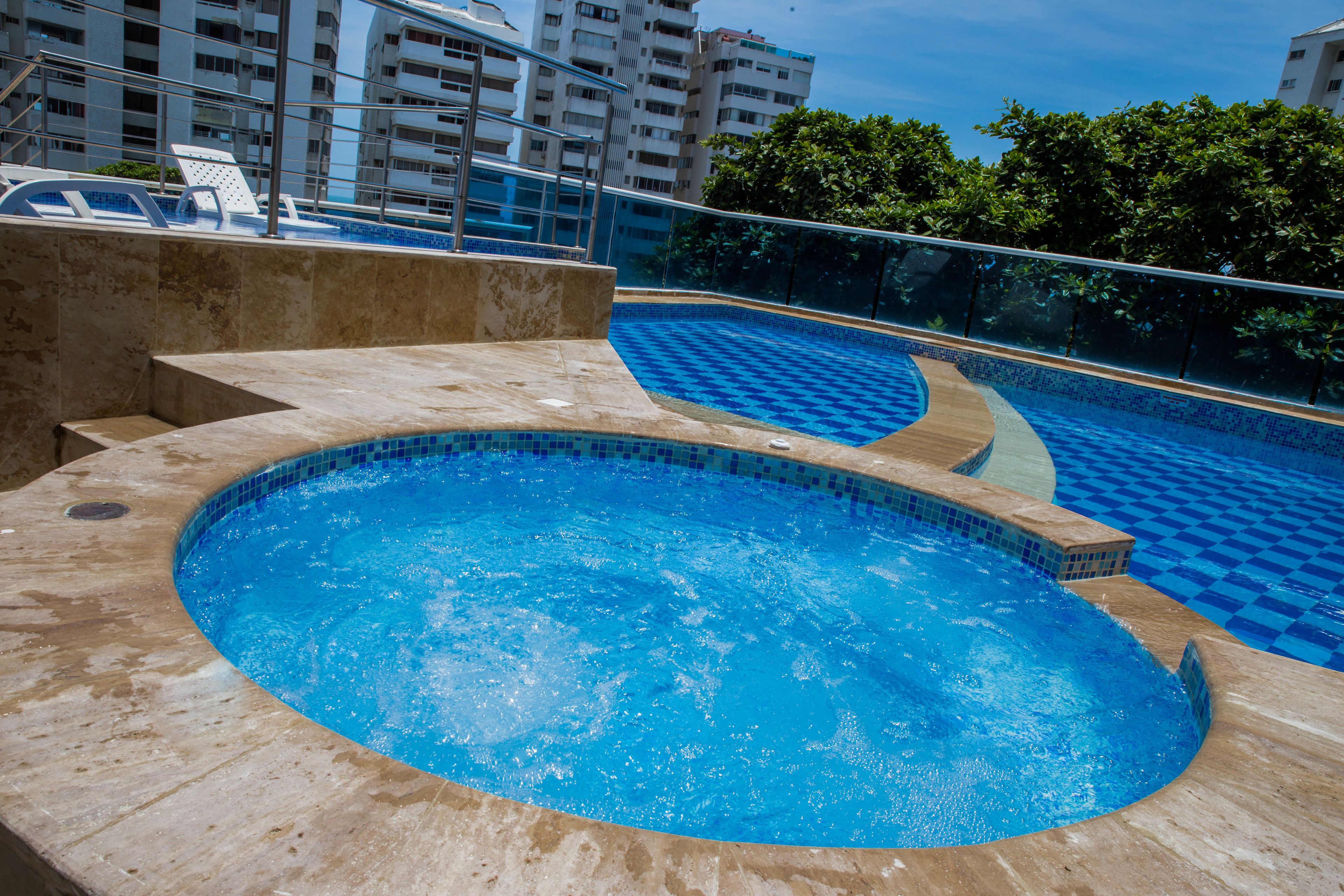 Una piscina con suelo de baldosas y barandilla de cristal.