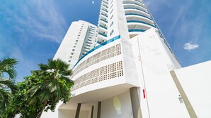 A tall, modern building with a curved facade and multiple balconies.