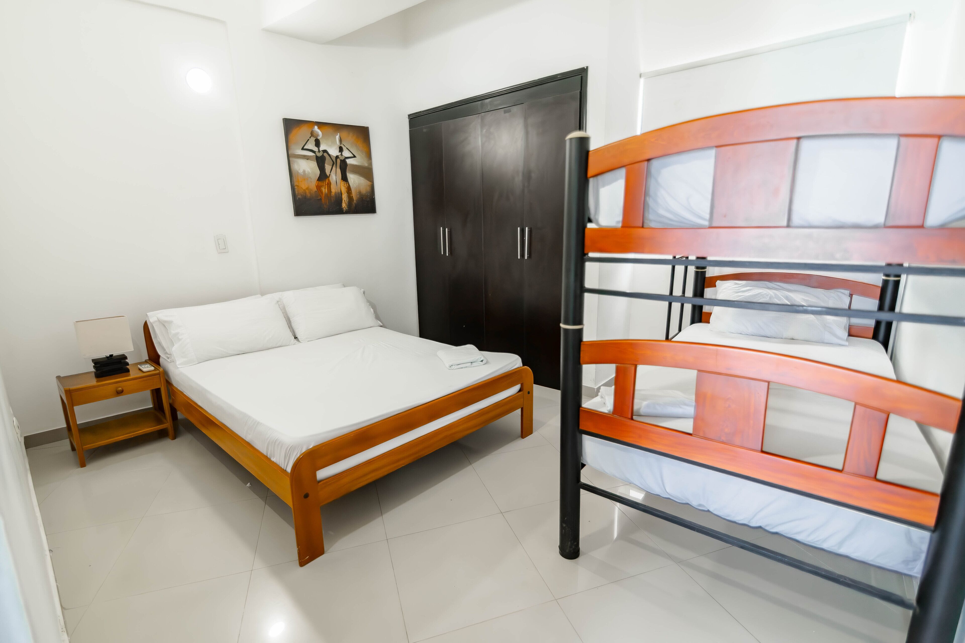 A bedroom with a wooden bed, a nightstand, a wardrobe, and a bunk bed.