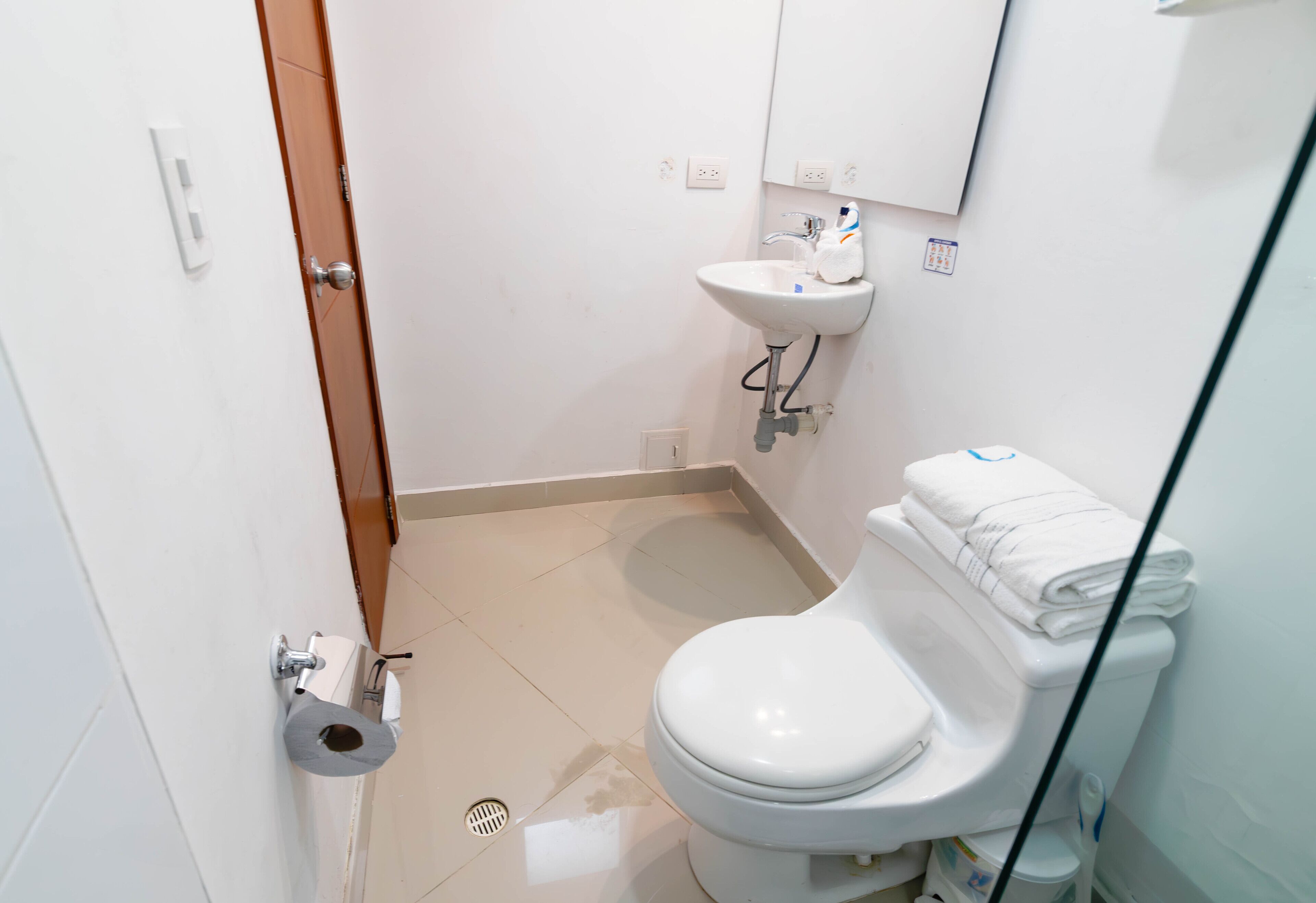Un baño pequeño y limpio con inodoro, lavamanos y espejo.