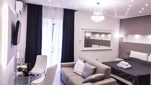 Quarto de hotel moderno com uma cama, um sofá, uma mesa de vidro e uma cadeira.