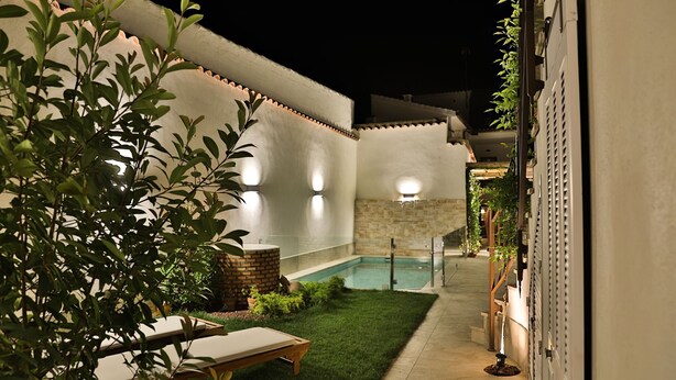 A poolside area with a small pool, a lounge chair, and a brick planter.