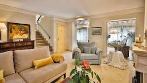 A living room with a sofa, armchair, and a staircase leading to another room.