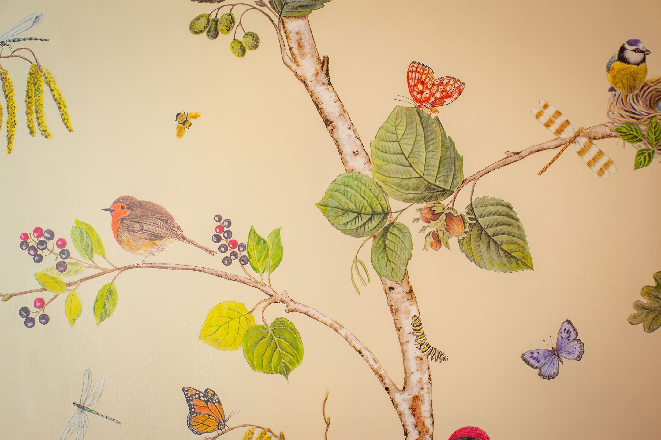 Un mural de un árbol con pájaros, mariposas y una libélula.