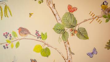 Un mural de un árbol con pájaros, mariposas y una libélula.