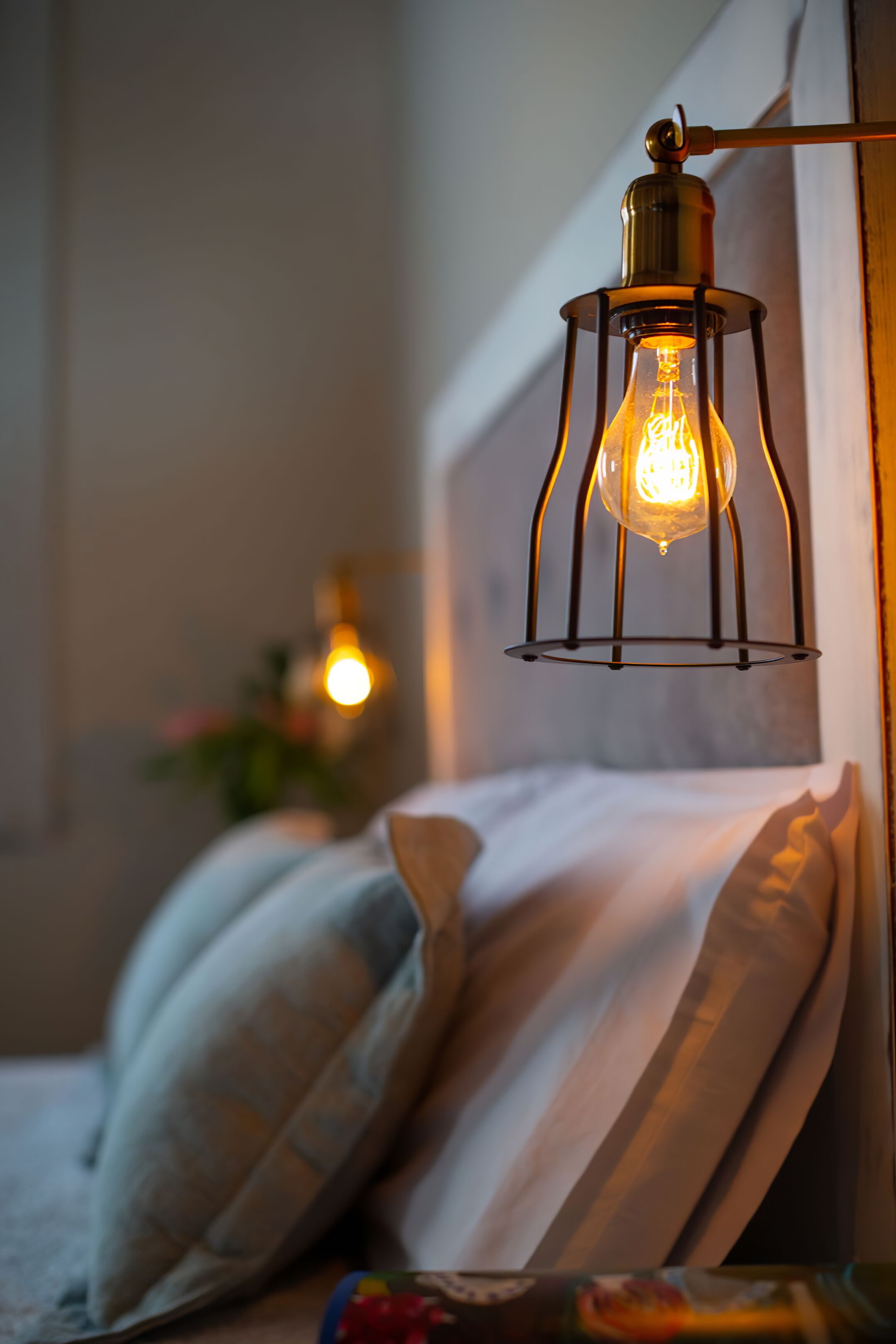 A bed with pillows and a hanging light fixture.