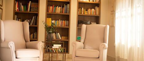 Una sala de estar con dos sillones, una mesa de centro y una estantería llena de libros.