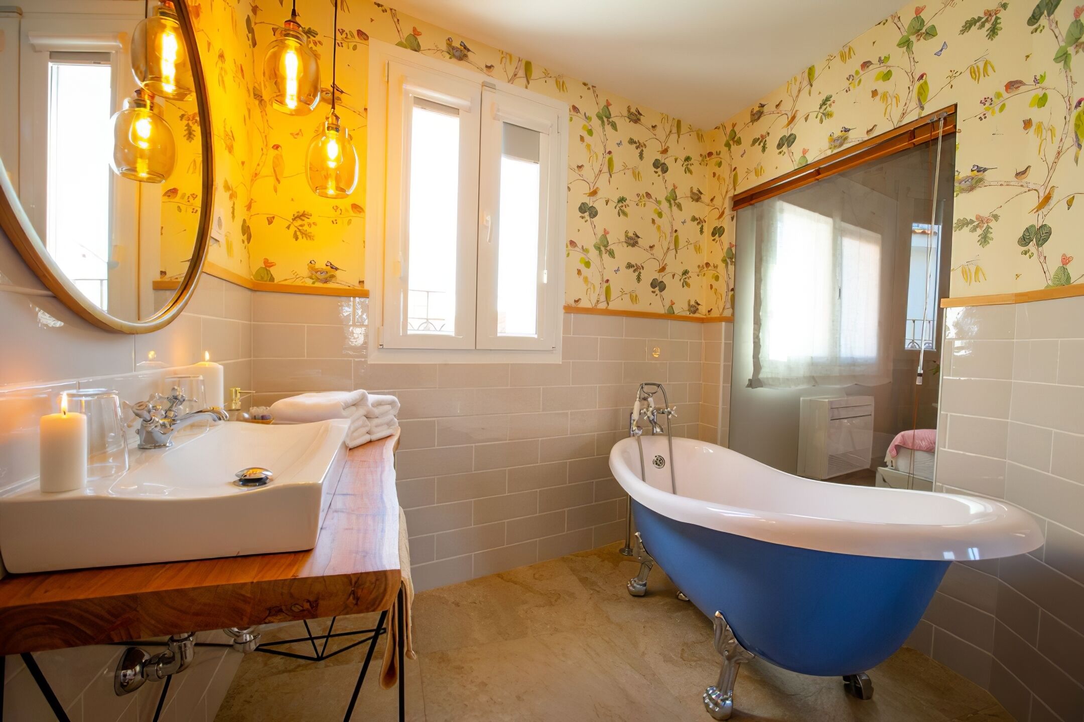 A bathroom with a white sink, blue bathtub, and floral wallpaper.