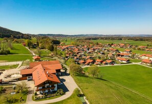 A residential area with houses having red roofs, surrounded by green fields and a few trees. - Hoderhof (Grassau)