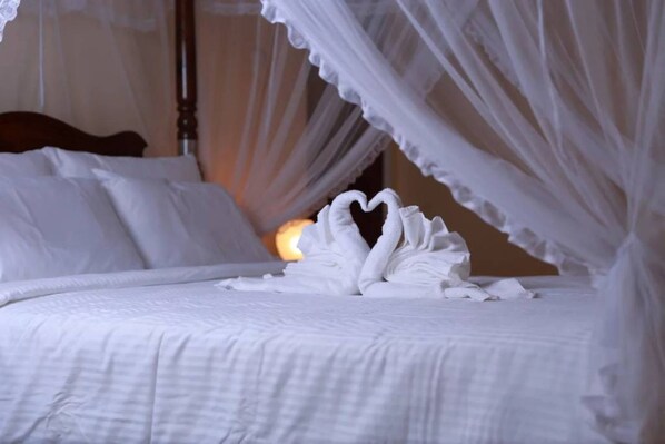 A bed with white bedding and a canopy.