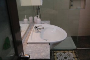 A bathroom with a white sink, a mirror, and toiletries on the counter.