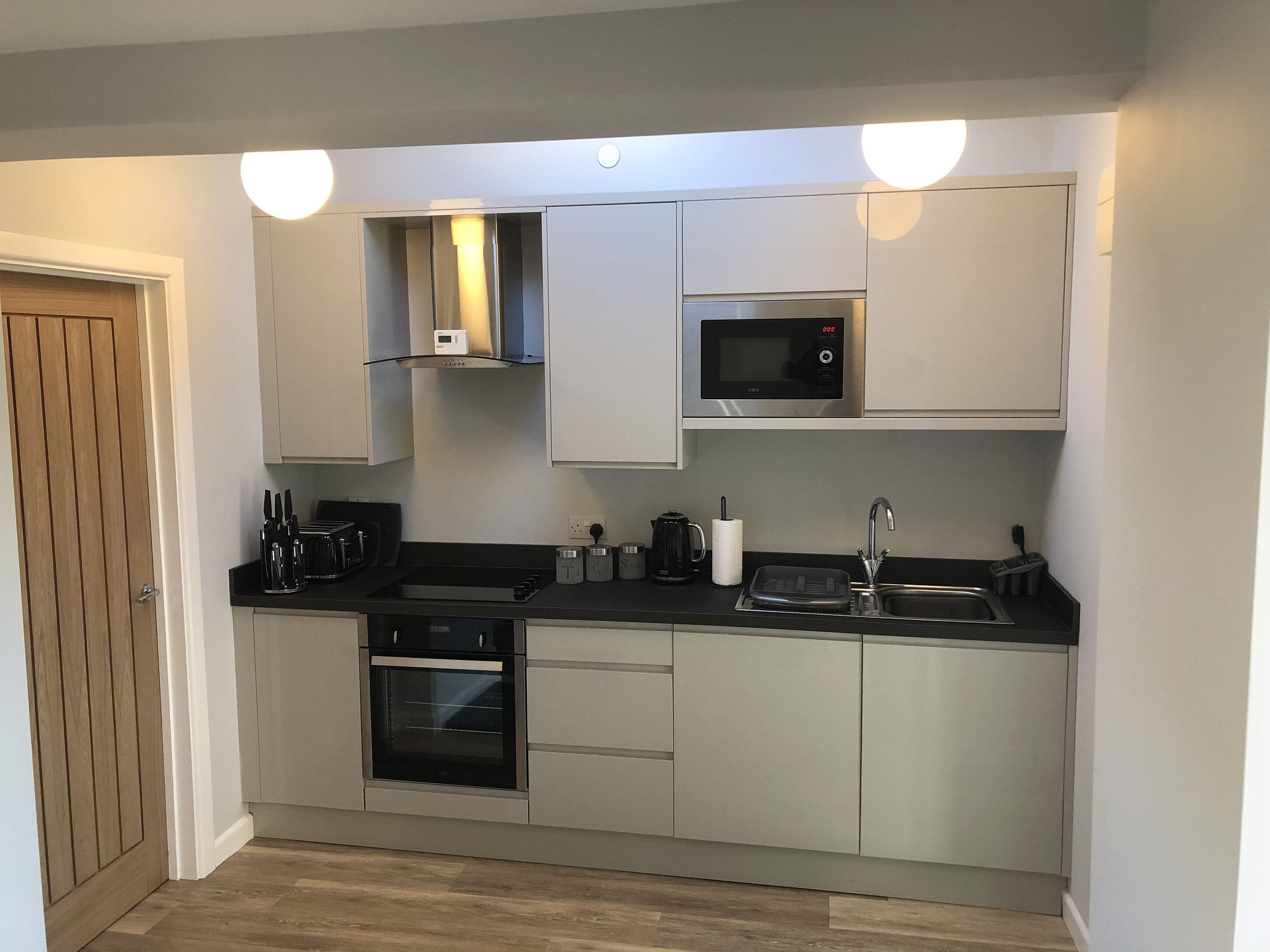 A compact kitchen with a microwave, oven, and sink.