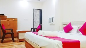 Une chambre d’hôtel avec un lit, un bureau, une chaise et une armoire.