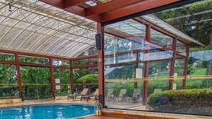 A hot tub area with a wooden deck, a glass-enclosed pool, and a view of greenery outside. - Esquilo Hotel (Camanducaia)