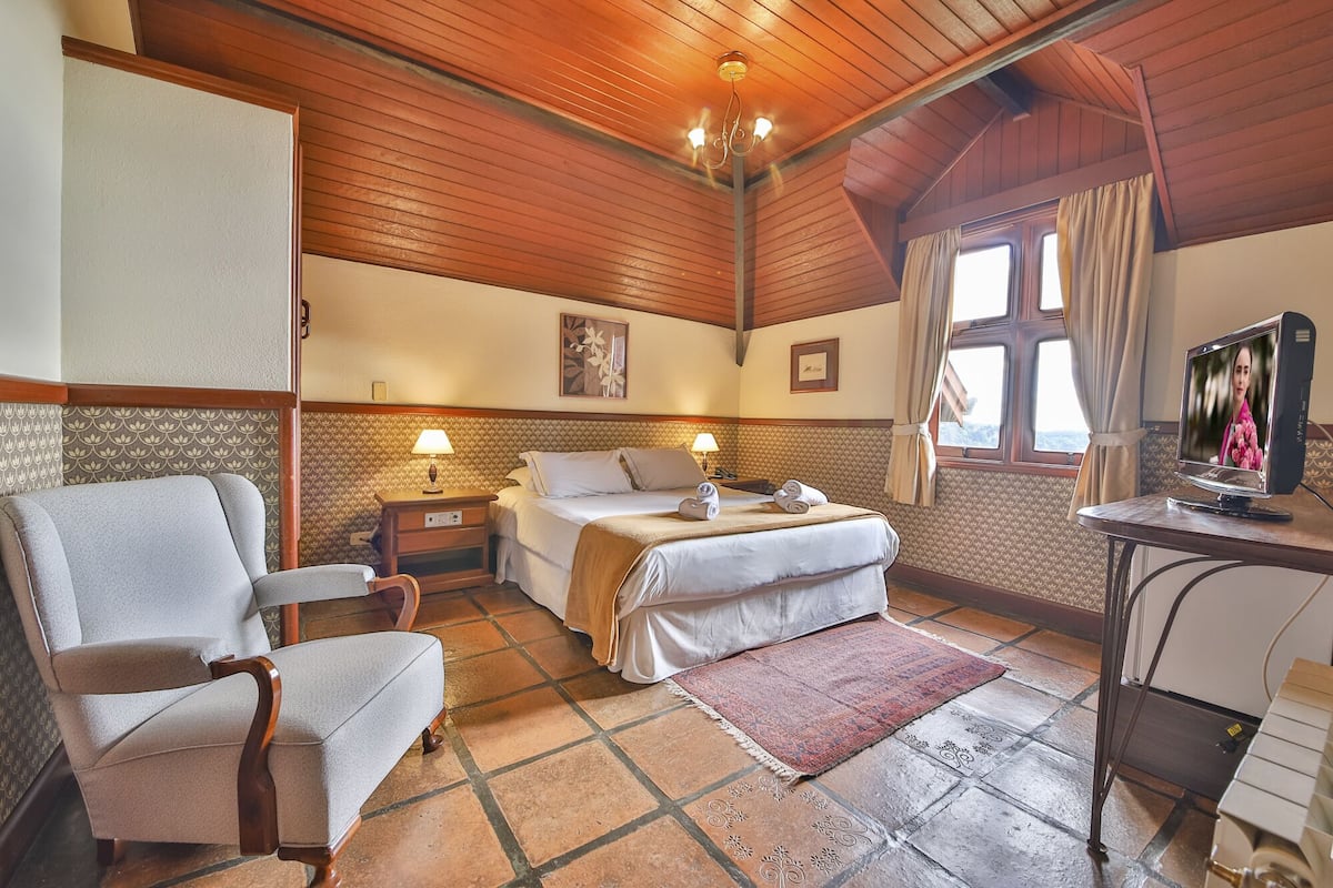 Une chambre d’hôtel confortable, avec un lit, un bureau équipé d’un ordinateur, une chaise et une télévision.