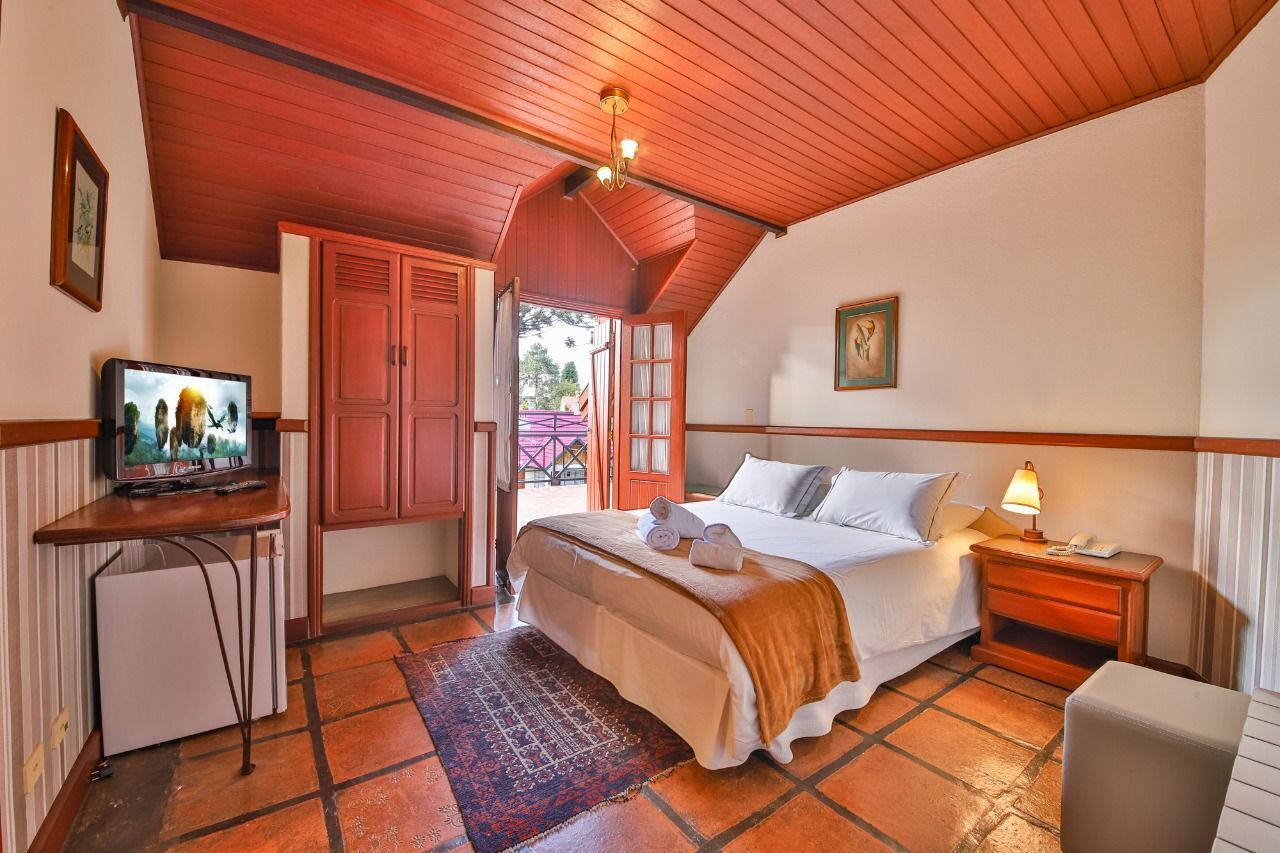 A bedroom with a bed, bedside table, lamp, and a television on a small table.