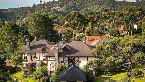 A large, multi-story house with a spacious backyard, surrounded by lush greenery and hills. - Esquilo Hotel (Camanducaia)