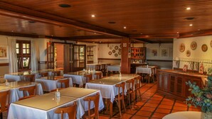 A restaurant with multiple tables and chairs, wooden ceiling, and tiled floor. - Esquilo Hotel (Camanducaia)