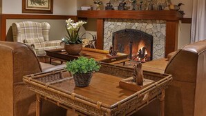 A cozy living room with a stone fireplace, wicker furniture, and decorative plates on the mantel. - Esquilo Hotel (Camanducaia)