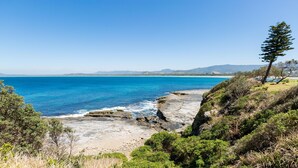 A coastal landscape with rocky terrain and dense greenery.